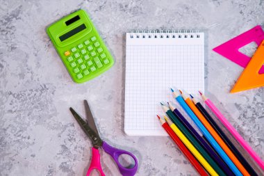 Kırtasiye seti, hesap makinesi, defter, renkli kalemler, cetvel, arka planda makas. Mesaj için alan, arkaplan. Düz yatış, üst görünüm