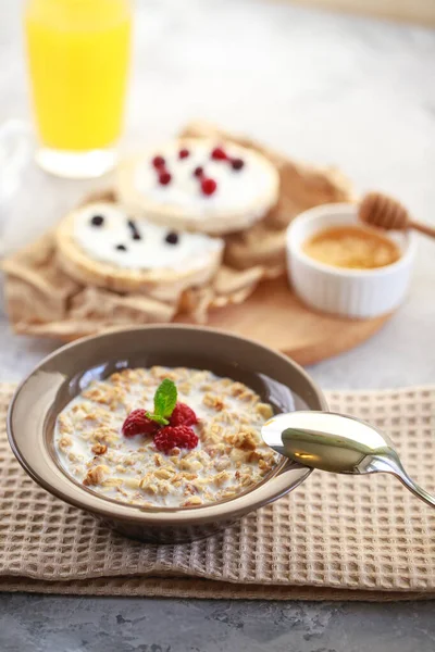 Baked granola with milk and raspberries in a plate, whole grain breads and freshly squeezed juice. A wholesome and dietary breakfast. Delicious muesli