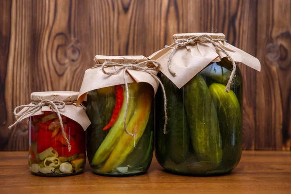 Ahşap arka planda cam kavanozlarda konserve sebzeler. Turşu. Salatalık ve biber turşusu.