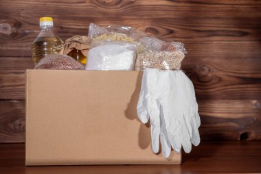 Yemek servisi. Coronavirus gıda bağışı. Eldivenli bir kutuda yiyecek, yakın plan..