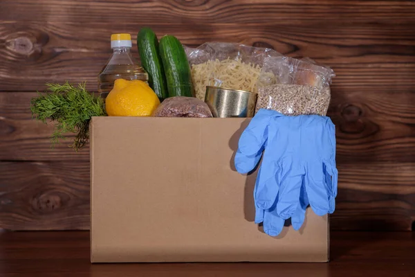Coronavirus food donation. Food in a box with gloves, close-up. Food delivery.