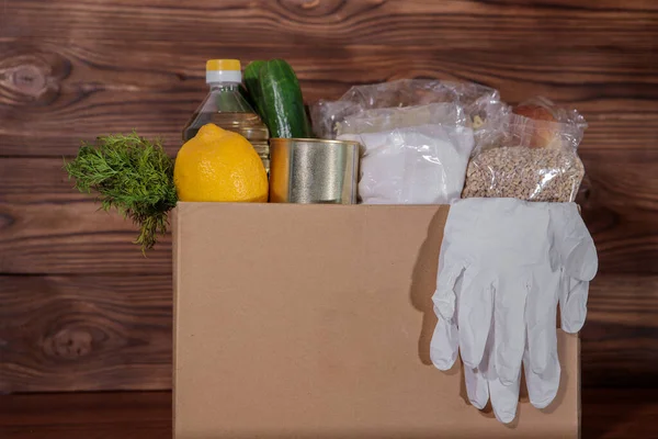 Coronavirus food donation. Food in a box with gloves, close-up. Food delivery.