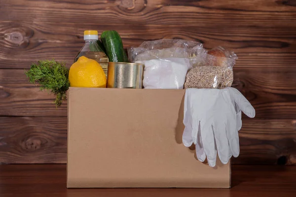 Food delivery. Coronavirus food donation. Food in a box with gloves, closeup.