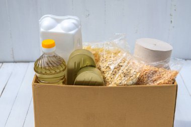 Coronavirus gıda bağışı. Beyaz arka planda ihtiyacı olanlar için bir kutuda yiyecek. Yemek teslimatı.
