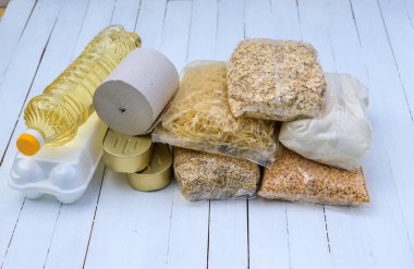 Muhtaçlar için bağış. Mısır gevreği, ovianka, inci arpa, bezelye, tuvalet kağıdı, konserve yiyecek, ayçiçeği yağı, beyaz arka planda yumurtalar. Düz yatıyordu.