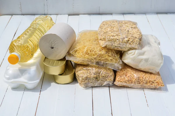 Donation of food for the needy. Set of cereals, ovianka, pearl barley, peas, toilet paper, canned food, sunflower oil, eggs on a white background. Flat lay.