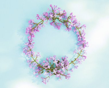 Mavi arka planda leylak çiçeklerinin yuvarlak çerçevesi. Çiçek kompozisyonu. Düz uzanış, metin için boşluk. Sevgililer Günü, Anneler Günü, Kadınlar Günü konsepti.