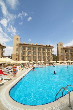 Güneşli bir günde havuzlu bir otel.