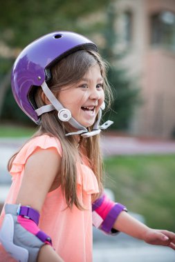 Parkta kaskla paten kayan küçük bir kız.