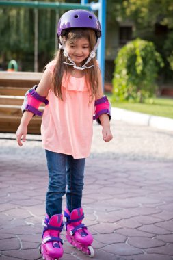 Parkta kaskla paten kayan küçük bir kız.