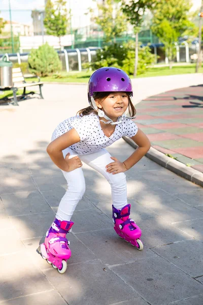 在公园里 穿着旱冰鞋的小女孩戴着安全帽 免版税图库照片