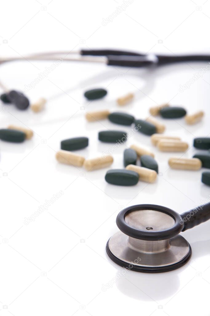 medical concept with lots of pills and stethoscope on white with shallow dof