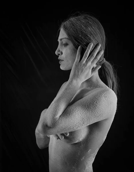 Mulher com pó no estúdio em um fundo preto — Fotografia de Stock