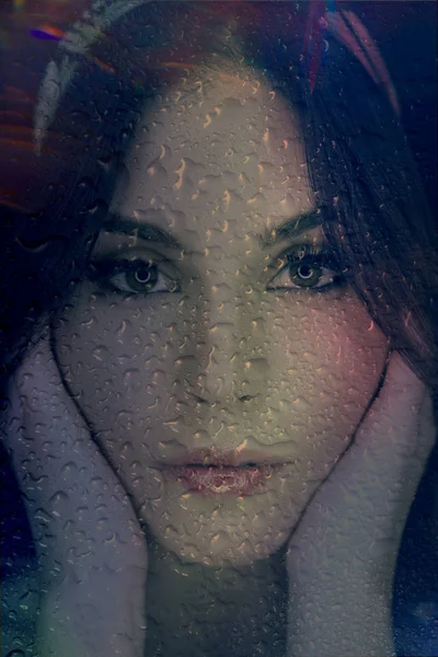 Face of beautiful romantic girl through a window glass with rain — Stok fotoğraf