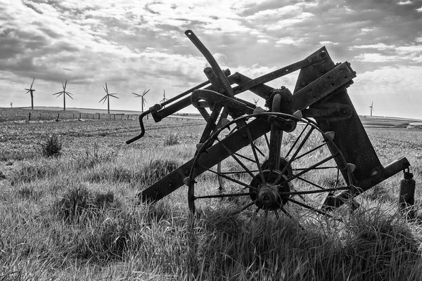 Old and new technology - wind turbines and abandoned plough - black and white