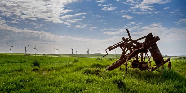 Tecnología antigua y nueva - turbinas eólicas y arado abandonado — Foto de Stock