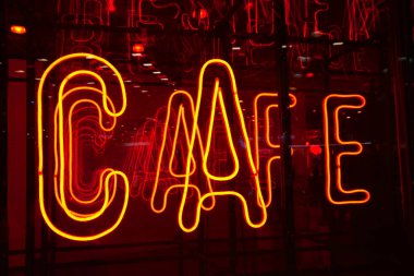 Kırmızı cam duvarda parlak sarı neon harflerle kafeterya tabelası