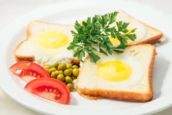 fried eggs in toast with tomatoes and green peas