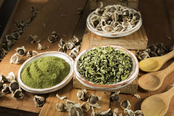 Moringa, yapraklar, tohumlar, tahta bir arka planda toz - Moringa oleifera