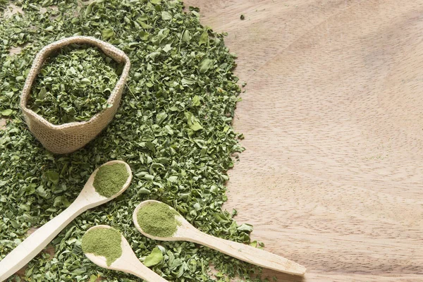 Moringa, ahşap bir arka planda yapraklar ve toz...