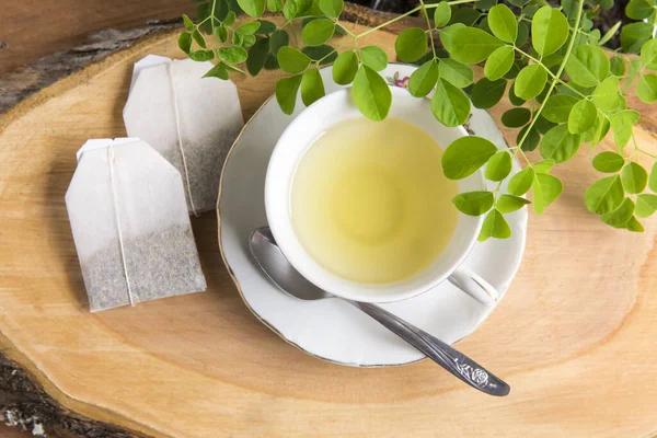 Moringa çayı, yapraklar, tohumlar, tahta bir arka planda toz - Moringa oleifera