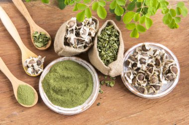 Moringa, hojas, semillas, polvo sobre un fondo de madera - Moringa oleifera