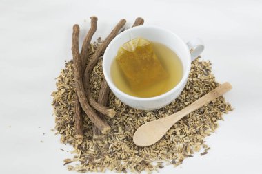 Meyan kökü ve zerdeçal karıştırılmış bir fincan. Beyaz arka planda kök ve tahta kaşık - Glycyrhiza glabra