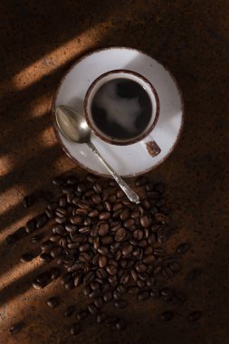 Tabak, kaşık, kahve ve kahve çekirdekleri. Hepsi koyu kahverengi arkaplanda