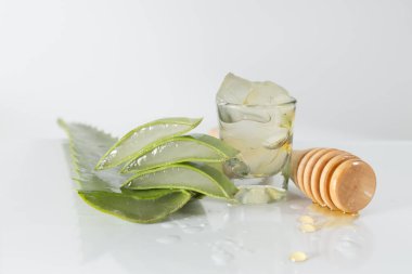 Beyaz arka planda dilimlenmiş aloe vera yaprakları ve bal kabı öğütücü