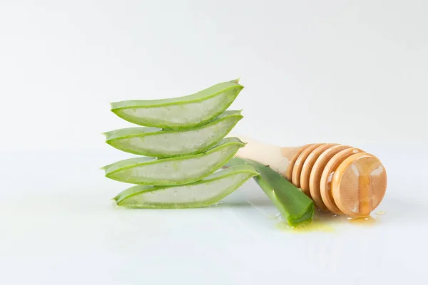 Beyaz arka planda dilimlenmiş aloe vera yaprakları ve bal kabı öğütücü