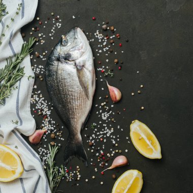 Tuz, biber, aromatik otlar ve sebzelerin vintage koyu arka plan üzerine taze balık .