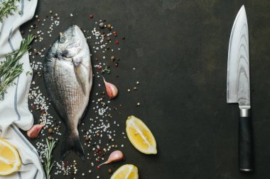 Tuz, biber, aromatik otlar ve sebzelerin vintage koyu arka plan üzerine taze balık .