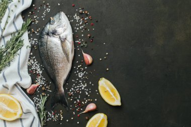 Tuz, biber, aromatik otlar ve sebzelerin vintage koyu arka plan üzerine taze balık .