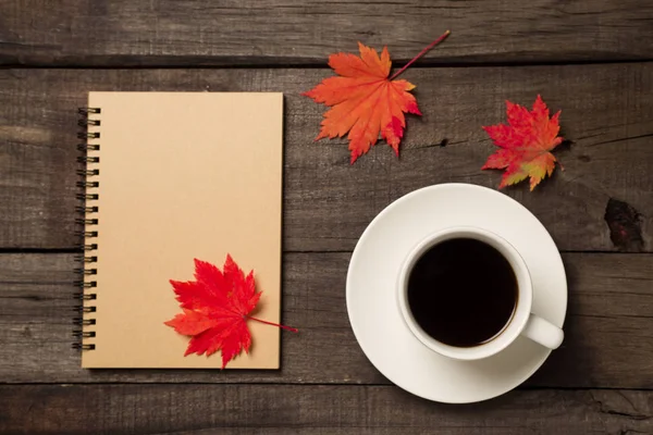 Sonbahar yaprakları ve bir fincan kahve ile ekose eski vintage ahşap arka plan üzerinde.