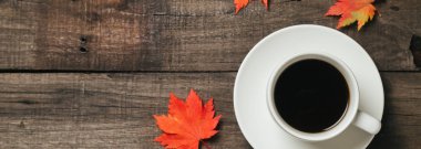 Sonbahar yaprakları ve bir fincan kahve ile ekose eski vintage ahşap arka plan üzerinde.