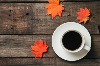 Sonbahar yaprakları ve bir fincan kahve ile ekose eski vintage ahşap arka plan üzerinde.