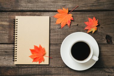 Sonbahar yaprakları ve bir fincan kahve ile ekose eski vintage ahşap arka plan üzerinde.