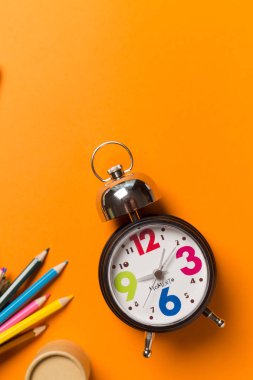Yuvarlak Saat ve kalem turuncu zemin üzerine ile kolaj. Zaman kavramı.