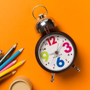 Yuvarlak Saat ve kalem turuncu zemin üzerine ile kolaj. Zaman kavramı.