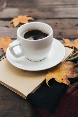 Ekose yaprakları ve bir fincan kahve eski vintage ahşap arka plan üzerinde sıcak sonbahar kompozisyonu.