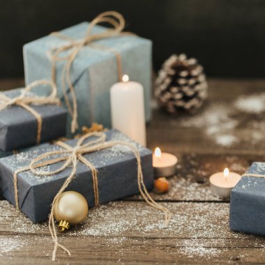 Festival hediye kutuları, mum, kar, iğne yapraklı, sepet, tarçın, çam kozalakları, deli ahşap arka plan üzerinde.