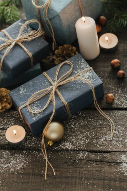 Festival hediye kutuları, mum, kar, iğne yapraklı, sepet, tarçın, çam kozalakları, deli ahşap arka plan üzerinde.