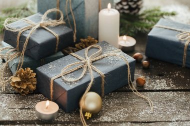 Festival hediye kutuları, mum, kar, iğne yapraklı, sepet, tarçın, çam kozalakları, deli ahşap arka plan üzerinde.