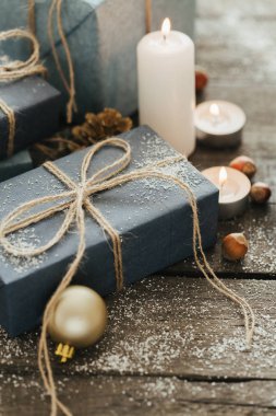 Festival hediye kutuları, mum, kar, iğne yapraklı, sepet, tarçın, çam kozalakları, deli ahşap arka plan üzerinde.