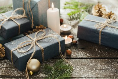 Festival hediye kutuları, mum, kar, iğne yapraklı, sepet, tarçın, çam kozalakları, deli ahşap arka plan üzerinde.