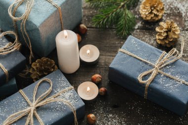 Festival hediye kutuları, mum, kar, iğne yapraklı, sepet, tarçın, çam kozalakları, deli ahşap arka plan üzerinde.