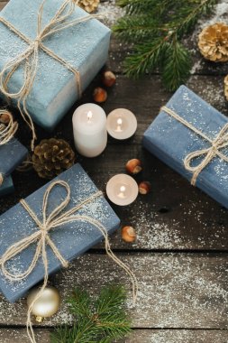 Festival hediye kutuları, mum, kar, iğne yapraklı, sepet, tarçın, çam kozalakları, deli ahşap arka plan üzerinde.