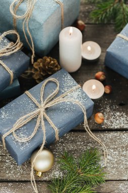 Festival hediye kutuları, mum, kar, iğne yapraklı, sepet, tarçın, çam kozalakları, deli ahşap arka plan üzerinde.