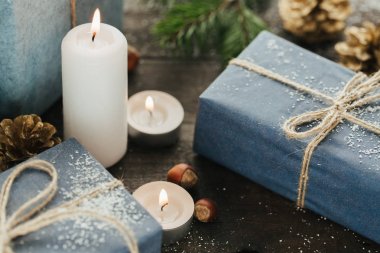 Festival hediye kutuları, mum, kar, iğne yapraklı, sepet, tarçın, çam kozalakları, deli ahşap arka plan üzerinde.