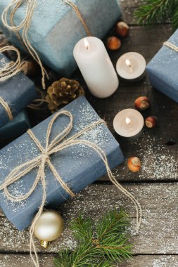 Festival hediye kutuları, mum, kar, iğne yapraklı, sepet, tarçın, çam kozalakları, deli ahşap arka plan üzerinde.